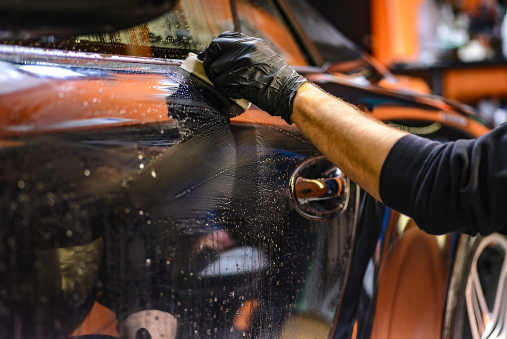 Man using an applicator brush to apply scratch remover to a car.