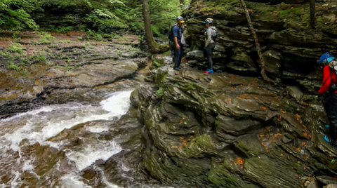 Alyssa and others navigate a rock ledge above a rushing river