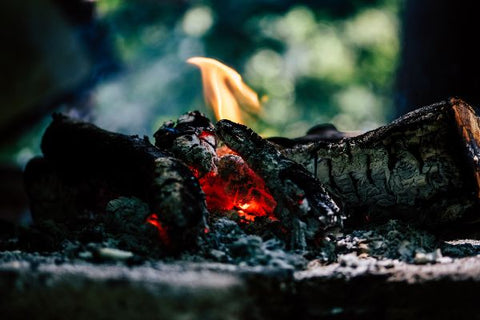 Asador tipo argentino; carbón consumiéndose con una llama