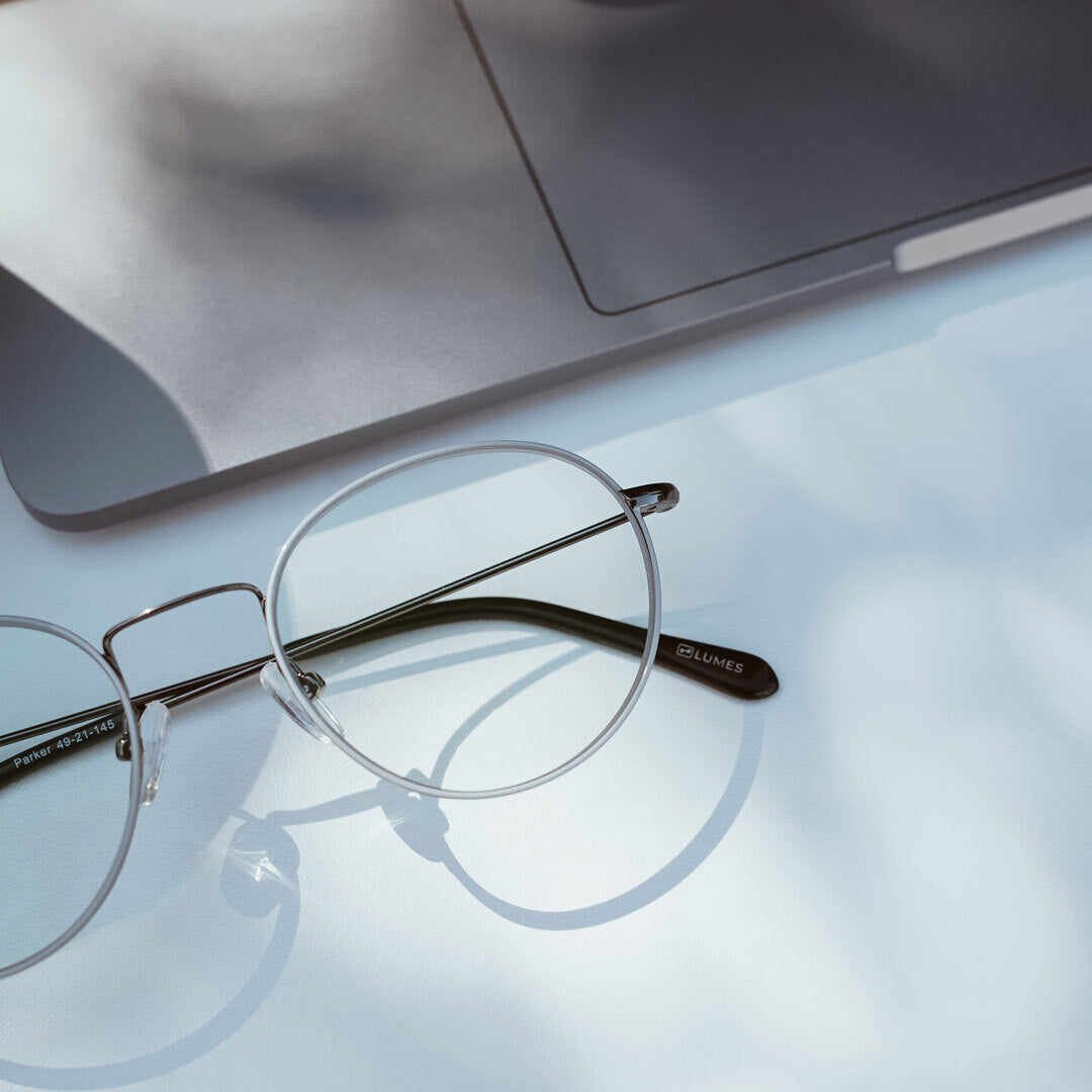 Close up of LUMES blue light glasses next to laptop