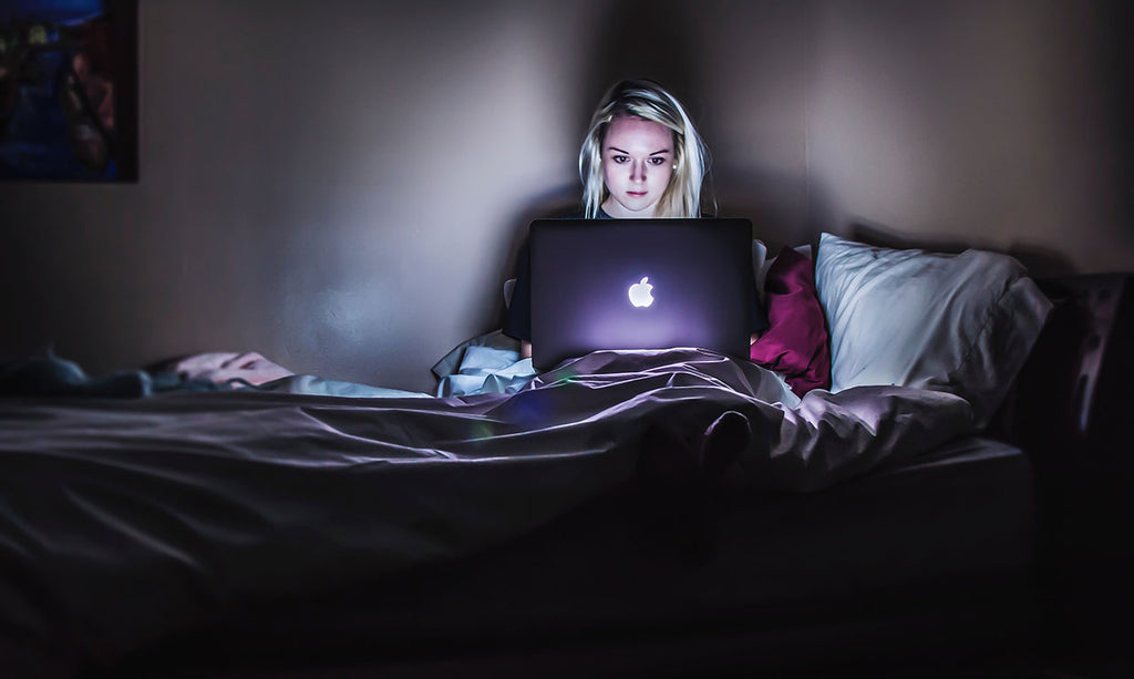 Woman using laptop in bed in night time