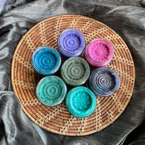 playdough in jars on a woven placement. featuring rich vibrant colours in magnenta, teal, navy, moss green, sky blue, purple and a galaxy inspired black, blue, purple swirl with glitter