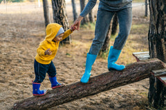 child taking a risk by climbing a branch with an adult