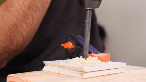 A man making a hole in the center of the wood square