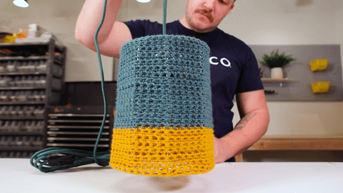 Person holding light fixture with knitted shade