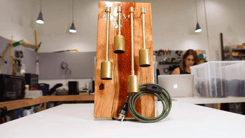 Wooden board holding bronze fixture pieces with curled electrical cord