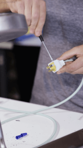 Hand with screwdriver on white electrical plug