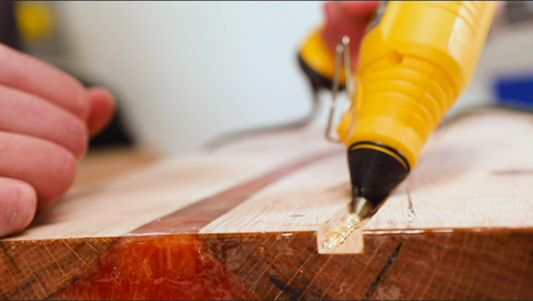 A man applying the glue in the routed portion of the wood slab