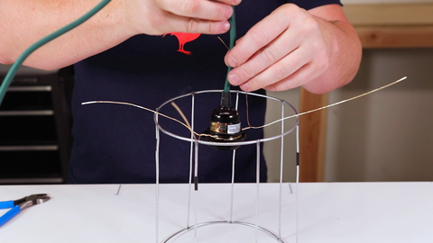 Electrical light cord placed on top of a wire lamp cage