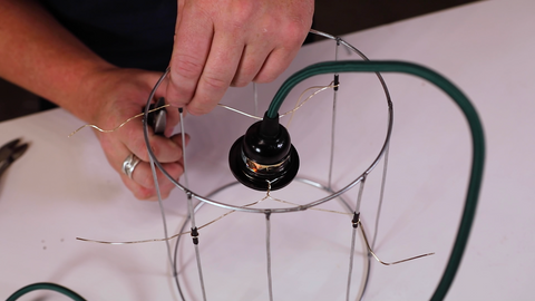 A man connecting the wire of the socket with the shade frame