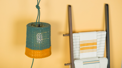 Pendant light with knitted shade next to towel ladder rack