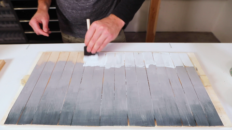 Man painting the gray gradient on the wooden shims