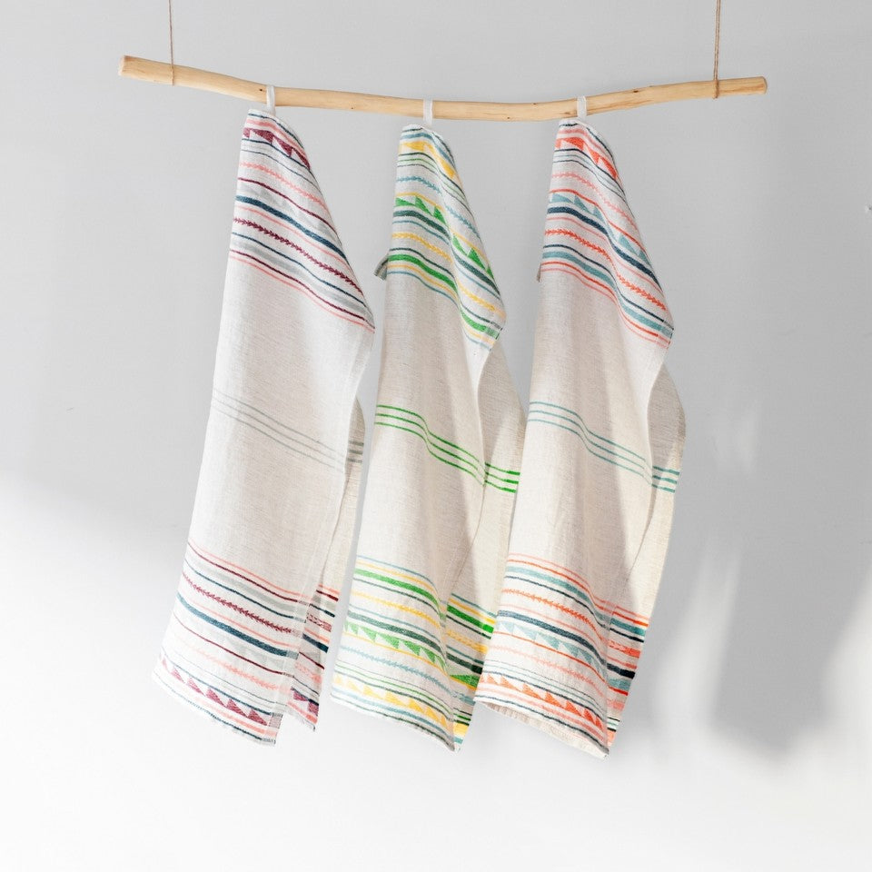 three Lapuan Kankurit tea towels hang off of a wooden dowel