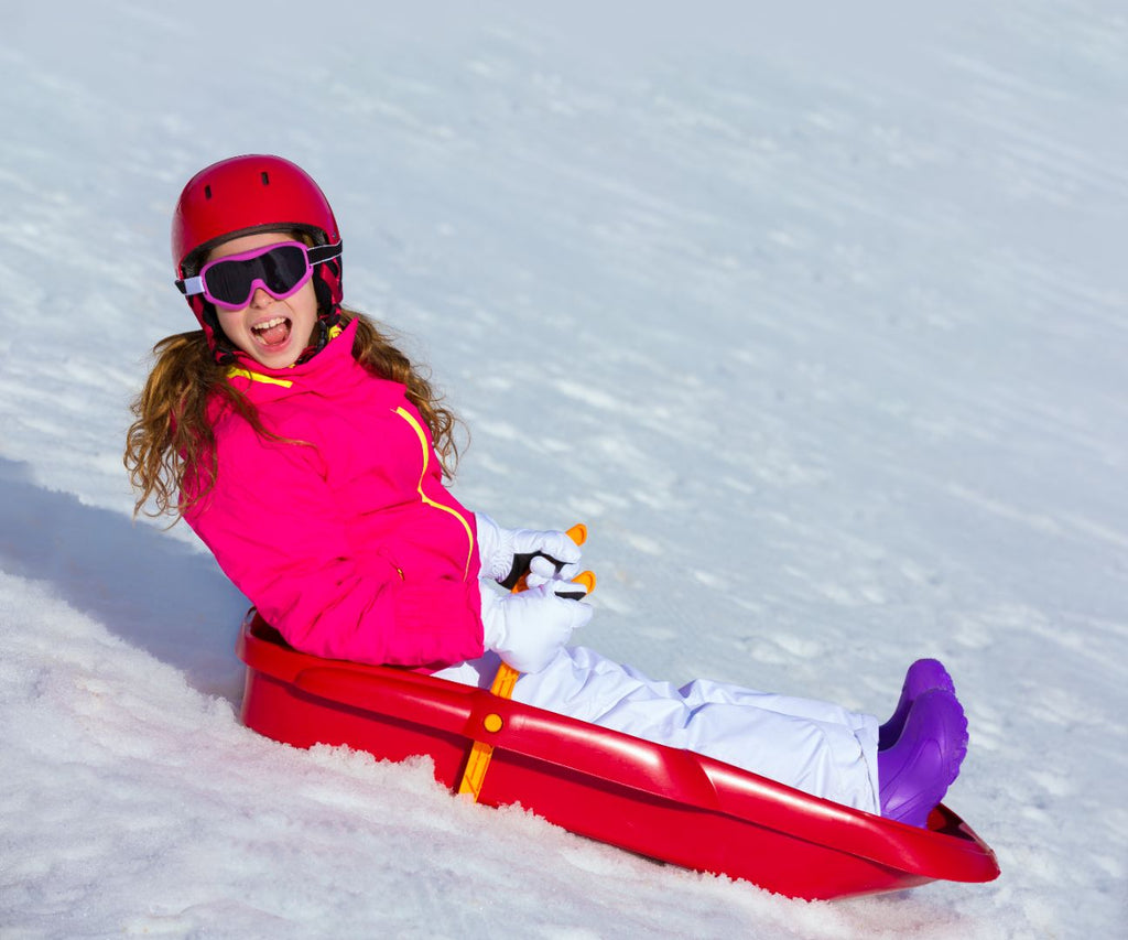 A girl wearing a helmet riding a winter sled