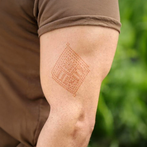 A muscular man with a geometric henna tattoo on his left arm.