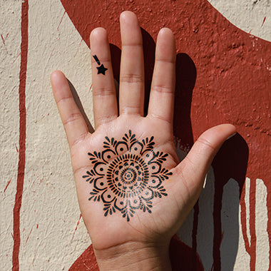 A black mandala jagua tattoo design on the palm.