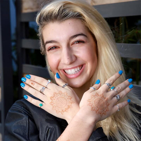 Smiling woman with mandala henna tattoos on the backs of her hands