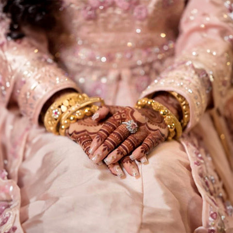 A pretty woman decorated with beautiful outfits, jewelry, and wedding henna designs on her arms.