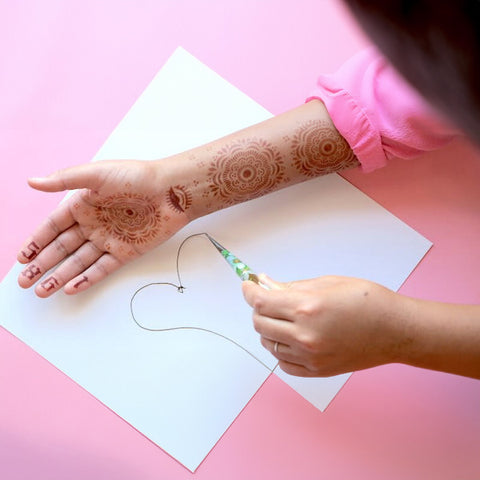 Girl practice henna tattoo designs on paper