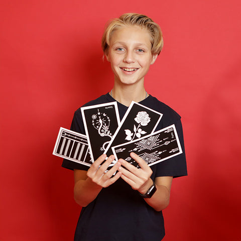 Boy holds up a selection of henna tattoo stencils