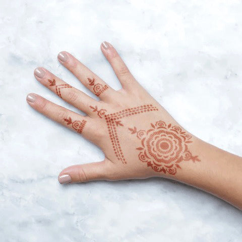 An image representing Camellia Stencil henna design on the backhand of a woman.