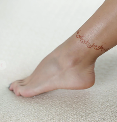 A woman adorned with the minimalist henna tattoo on her ankle.