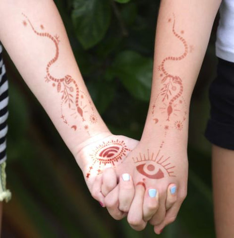 Two people holding hands adorned with modern henna tattoo designs.