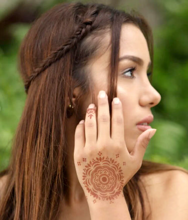 A woman showing off her backhand mandala henna tattoo complemented by a ring