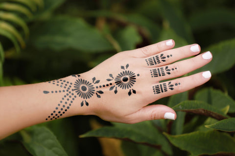 A woman’s left hand is adorned with a pearl jagua design and complimented by white nail polish.