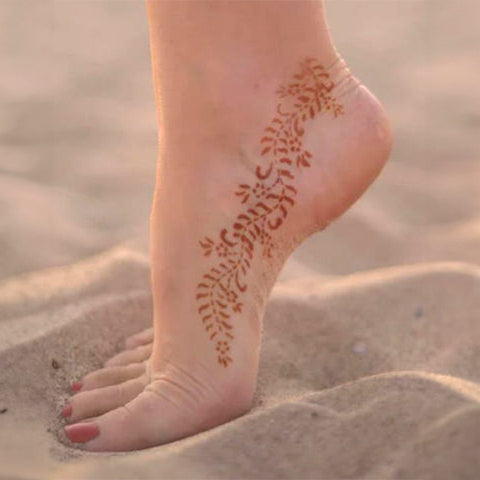 A pretty woman displaying an ivy henna tattoo on her foot.