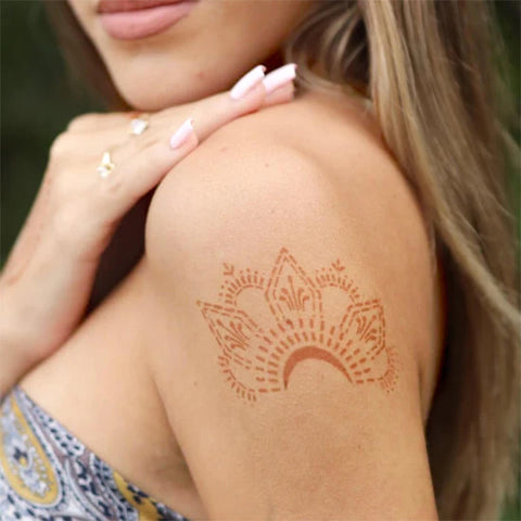 A pretty woman displaying a knuckle star henna tattoo on her shoulder.