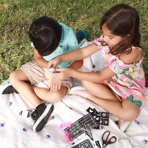 A photo of a girl applying Mihenna’s henna to a boy using henna cone & stencils