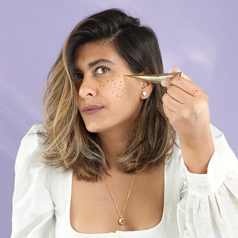 A Woman Wearing White Applying Faux Henna Freckles Using A Henna Cone.