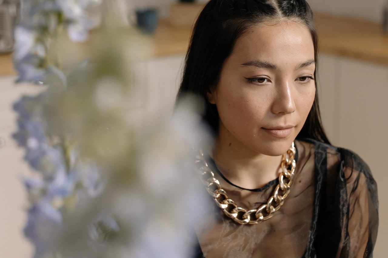 A woman sports a chunky gold chain necklace at a restaurant.