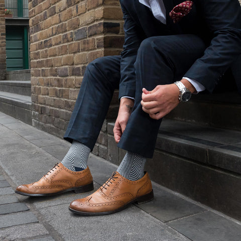 Man wearing a suit fixing his trousers and showing Lux Taylor socks.