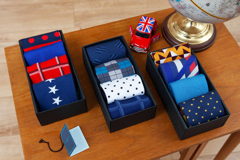 3 Peper Harow gift boxes full of luxury Peper Harow socks on a table next to a globe and a mini