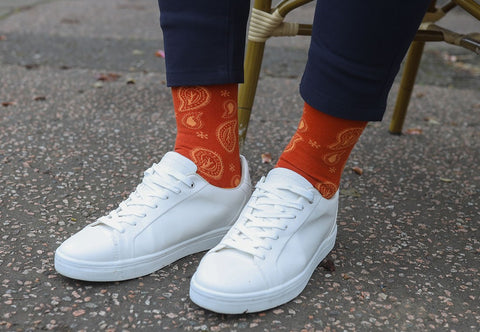 Man wearing white sneakers, navy trousers and orange Paisley organic cotton men's socks