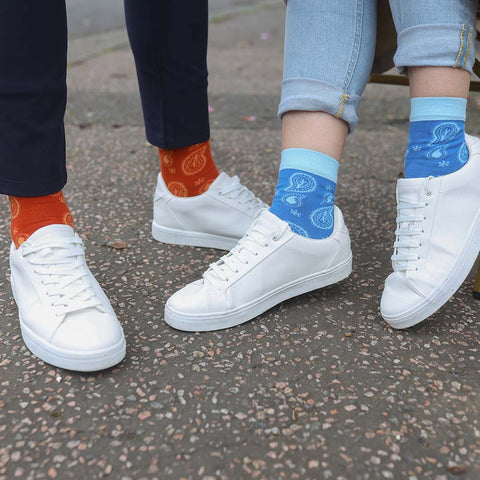 Man and woman outside wearing white sneakers, Paisley luxury socks from Peper Harow and trousers.