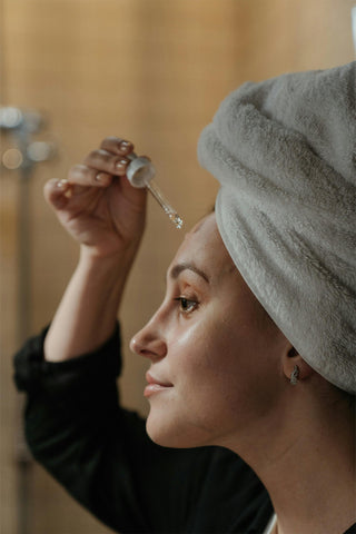 Woman applying a serum to her face.