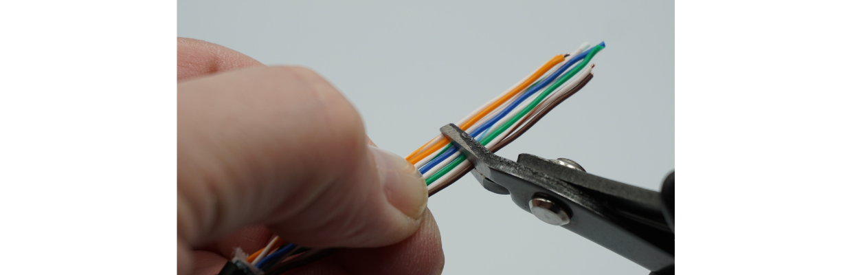 Locate a good spot, about 1.5 to 2” away from the cable jacket, to flush cut the conductors. T568B sequence shown. I like to work from top down (if I can). White-orange at the top, and solid brown at the bottom.