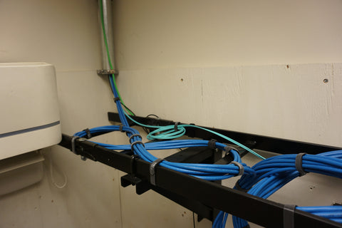 Telecommunications room in a commercial building.  The conduit is bringing in the drops to the ladder rack and the service loops are stored and attached to the ladder rack.  Note the figure “8” pattern.