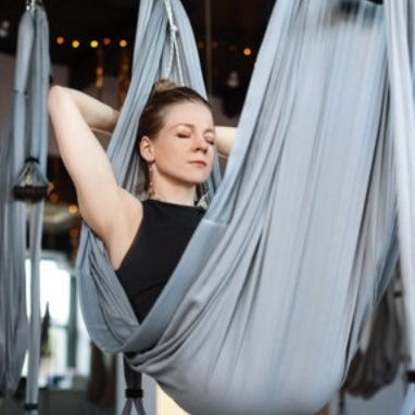 Woman relaxes in a yoga swing durning a Sound Healing Sound Bath meditation