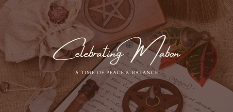 Text reading "Celebrating Mabon: a time of peace and balance" over a picture of an open journal besides a wooden box with a pentagram carved into it, a crystal, and plant.