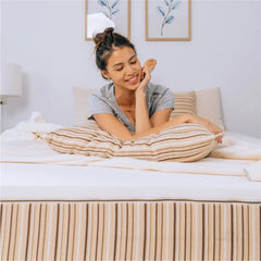 Une jeune femme se relaxant sur un matelas biologique REM5 Essentia. Elle pose ses coudes sur un oreiller Essentia.