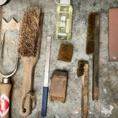 A collection of cleaning kit for gardening tools including garden tool brush, Niwaki Crean Mate and Niwaki Camelia Oil - shown with a Sneeboer Old Dutch hoe