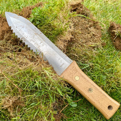 Serrated Hori Hori garden knife on a pile of turf after cutting it. 