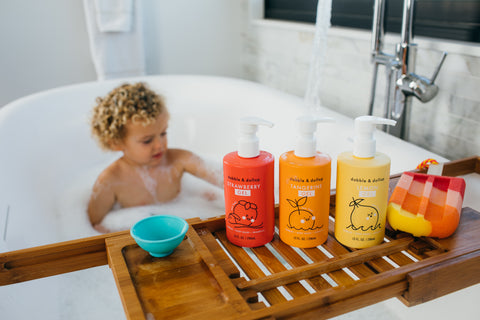 boy in tub looking at three bottles of bubble bath