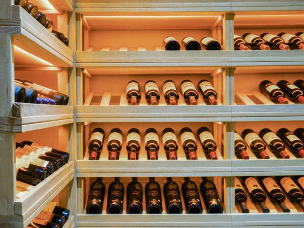 Assorted bottles of premium wine stored on wooden racks in a well-lit wine cellar at TipsyTopsy Singapore.