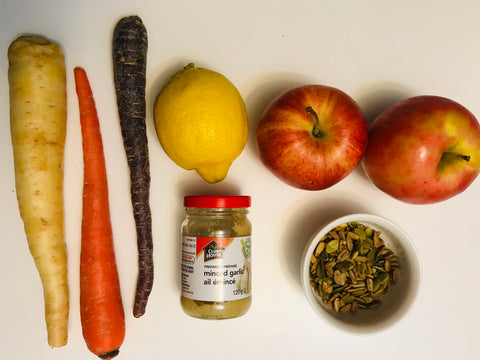 Ingredients for tahini carrot slaw. Carrots, lemon, seeds, garlic, and apples.