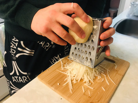 Grating celery root on a bamboo cutting board